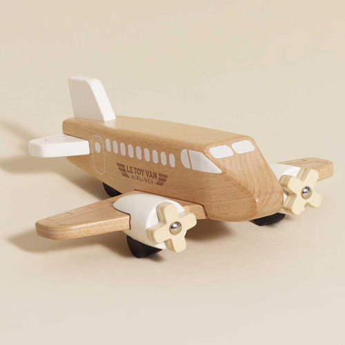 Sleek wooden commercial airplane toy by Le Toy Van with spinning propellers, white accents, and exposed natural wood grain.