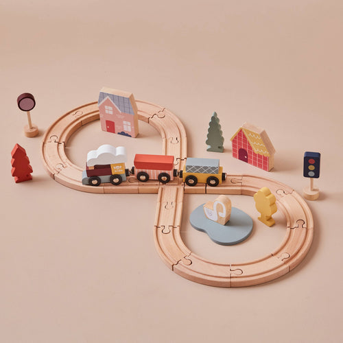 Scandi-inspired wooden train set by Just Bee Kids with track, train carriages, charming houses, and natural landscape accessories like trees and a swan in a lake.