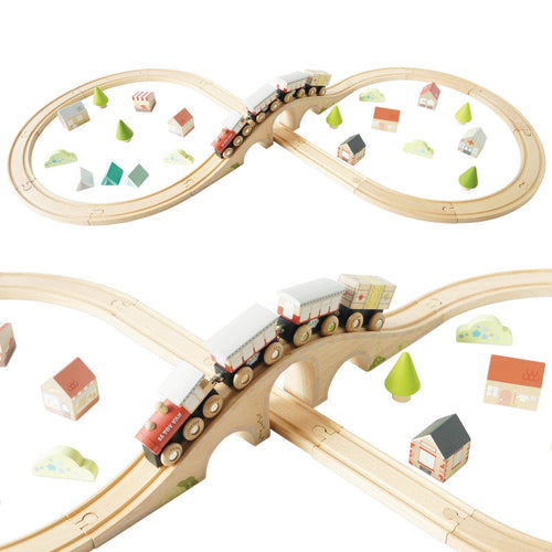 40-piece wooden train set by Le Toy Van with a figure-of-eight track, magnetic carriages, bridges, a station, houses, and wooden trees.
