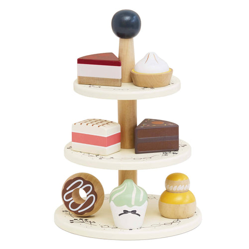 Wooden Three Tier Cake Stand by Le Toy Van with seven painted wooden sweet treats, including cakes, choux buns, and a doughnut.